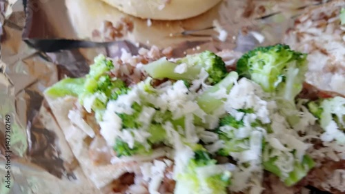 Preparing homemade vegetable flatbread with broccoli, mushroom, and cheese on foil for a healthy meal.