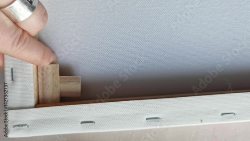 Closeup sequence of canvas stretching and stapling process for art preparation.