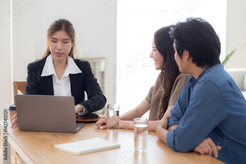 Happy asian couple discussion with real estate agent or insurance agent for investment in home office, mortgage loan or property purchase home, sale explaining insurance plan with couple.