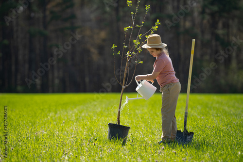 Obraz na płótnie Kid gardening. Child cultivating a tree in garden. Child planting tree. Little gardener working with shovel. Spring gardening with kids. Child watering plants in garden. Child taking care of garden. w salonie