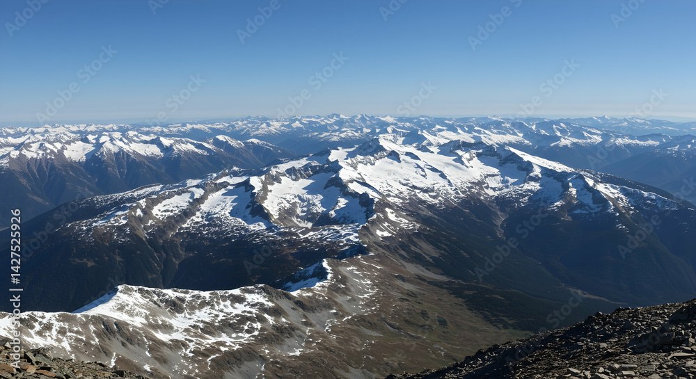 Fototapeta premium Breathtaking aerial view of rugged snow capped mountain range under clear blue sky ideal for travel and adventure themes
