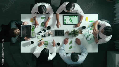 Top down view of business team discussing about using clean energy and sustainable investment at meeting table with wind mill, document with environmental graph and wooden house model. Alimentation.