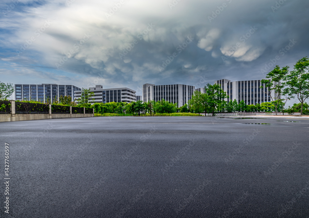 Empty asphalt road with modern office buildings under cloudy sky