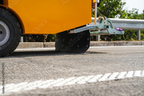 Low angle close-up of road marking machine near white rumble strip lines on highway under construction