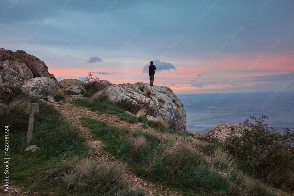 Hiker on the mountain summit at sunset.