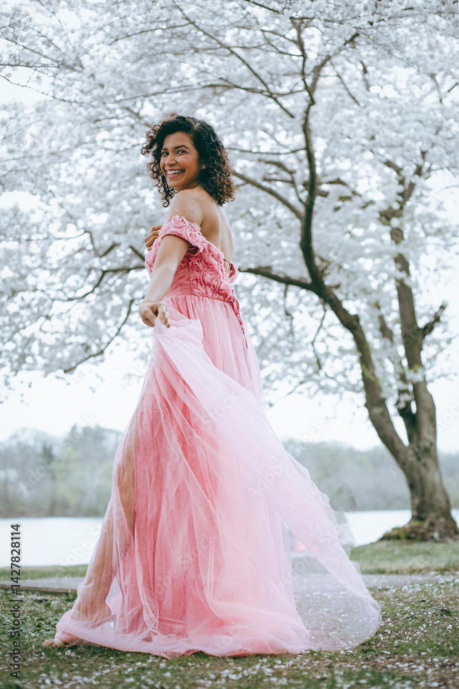 A woman in a long pink dress against the background of cherry blossoms A woman in a long pink dress against the background of cherry blossoms