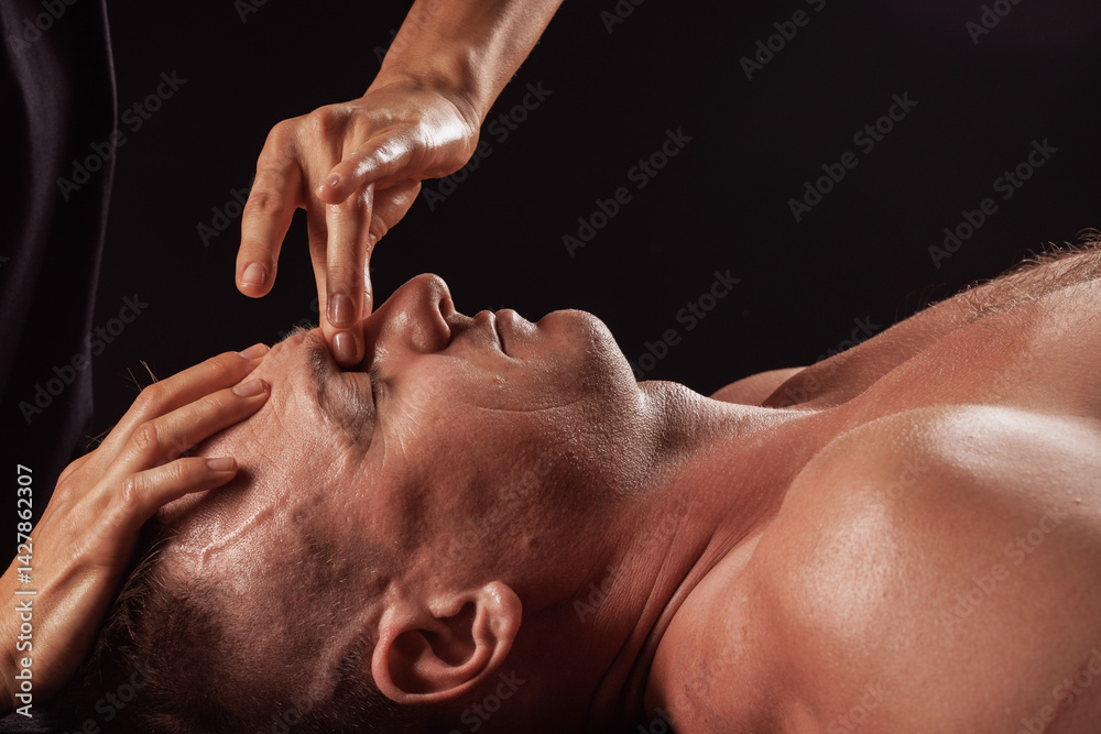 Naklejka premium Facial massage with finger pressure on brow ridge for relaxation and muscle tension relief.