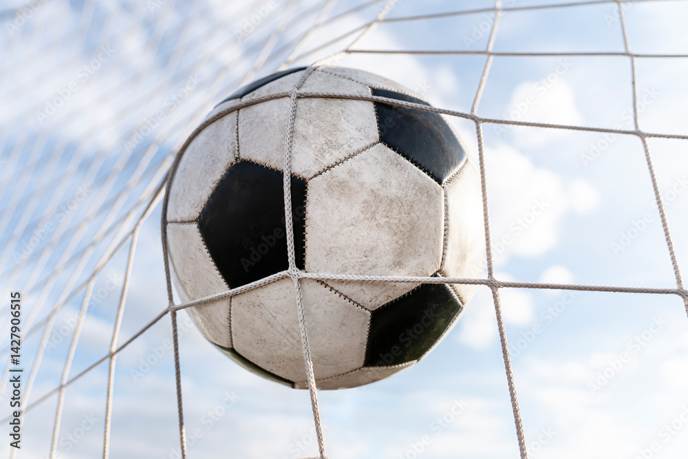 Symbolic of success and victory. classic soccer ball football have black and white color going into in-goal net after shooted in the game with a blue sky background. success concept.