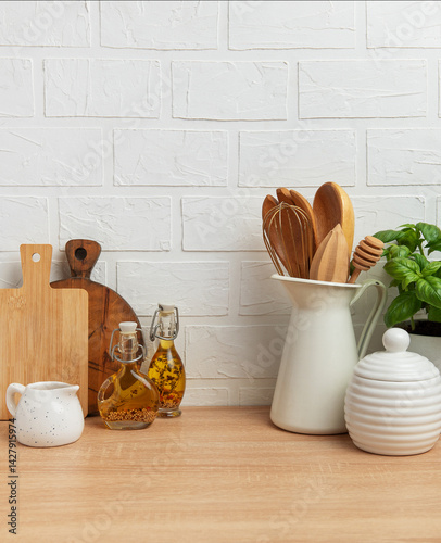 Obraz na płótnie Kitchen utensils, basil plant and condiments resting on wooden countertop in front of white brick wall w salonie