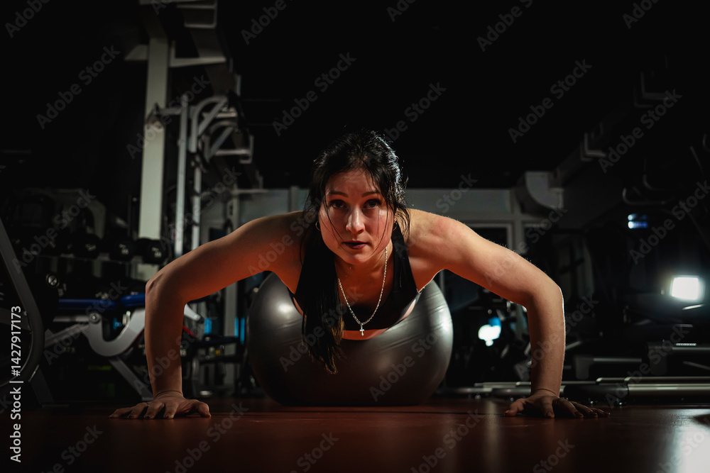 Fototapeta premium Gorgeous woman warming up and doing some push ups a gym, Sports concept healthy lifestyle and fitness. the concept of a sporty lifestyle.