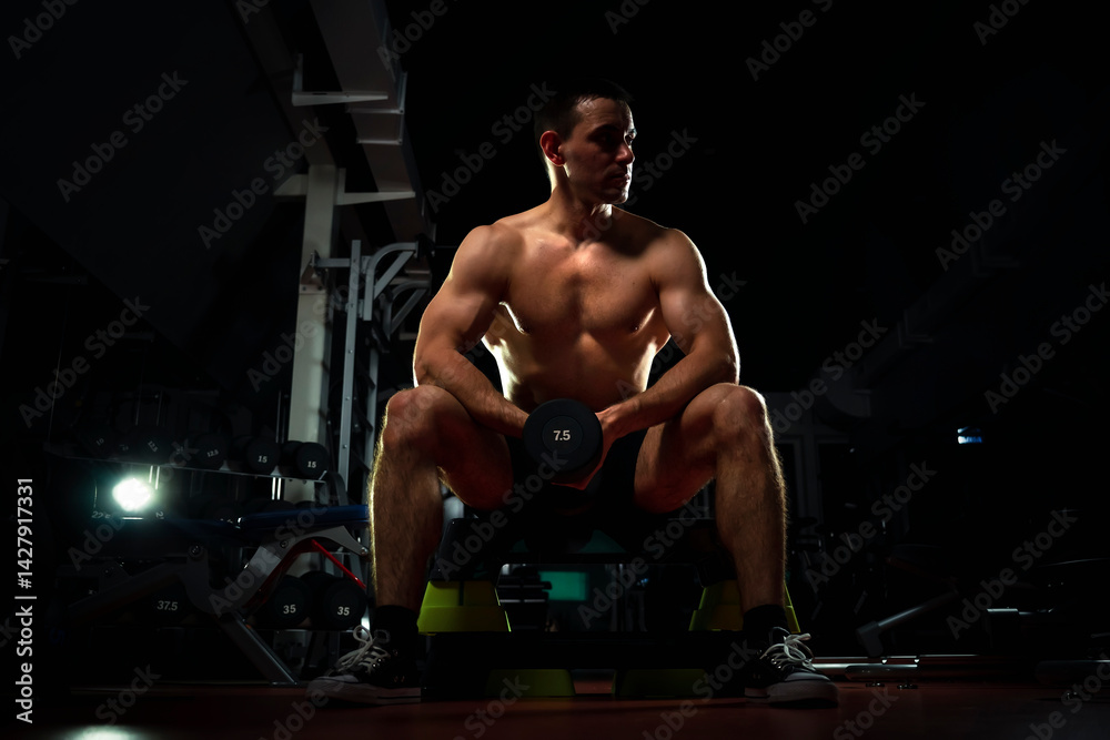 bodybuilder doing heavy weight exercise for biceps with dumbbell. concept of sports and training. Muscular man with dumbbells in a dark gym