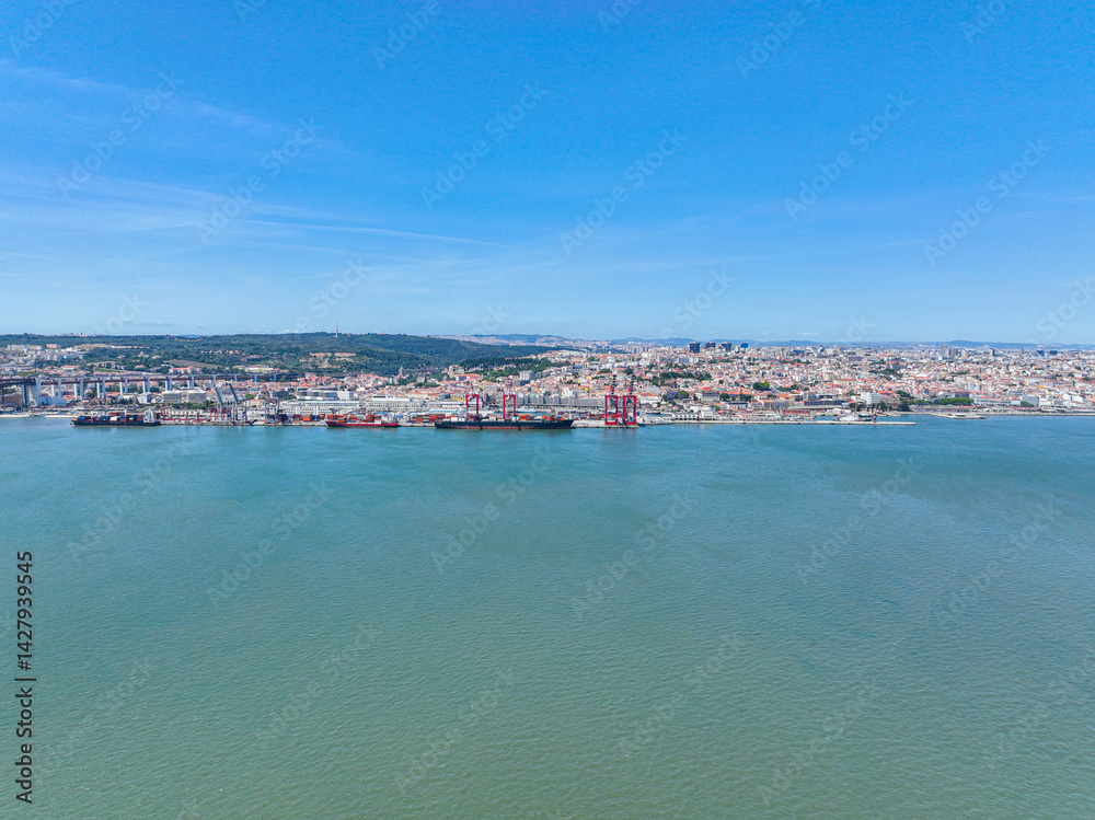 Fototapeta premium Aerial view of the Ports of Lisbon with large cargo ships and red cranes along the waterfront