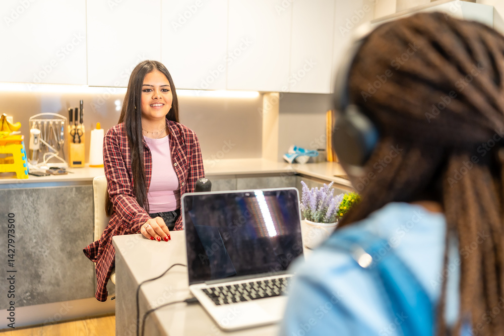 Teenage girls recording podcast in home studio using laptop and microphone
