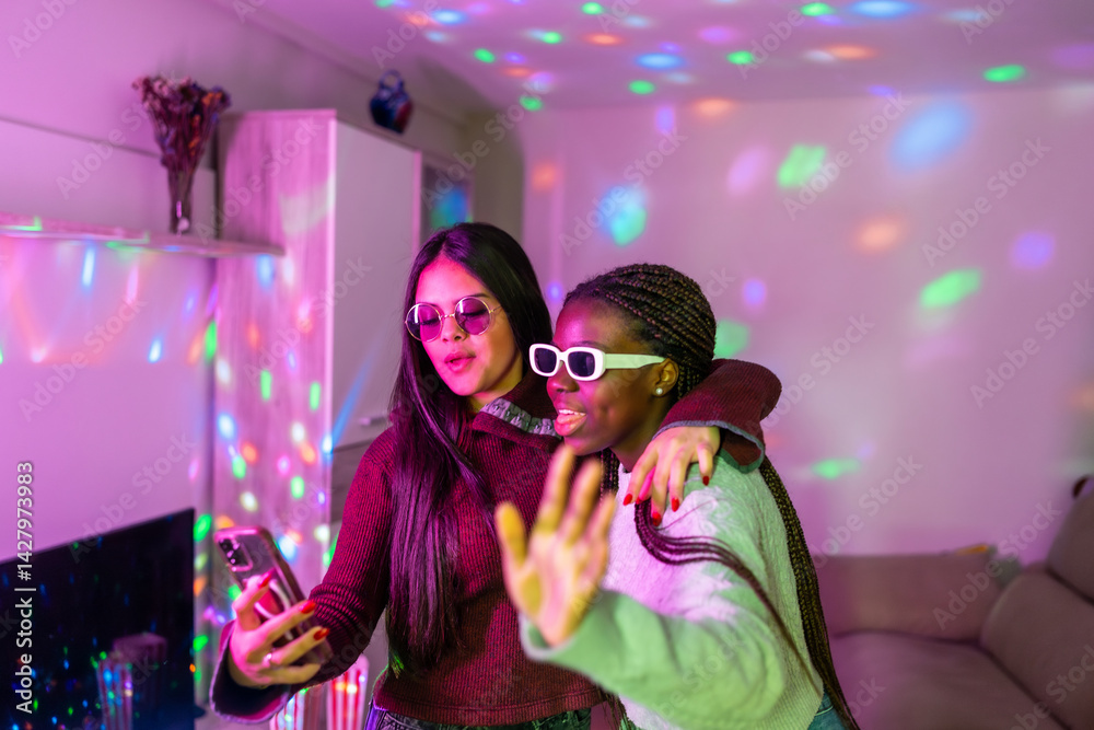 Two teenage girls embracing and taking selfie with smartphone at home party