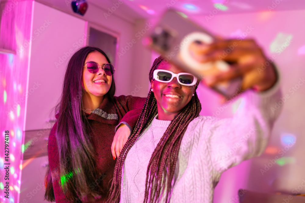 Teenage girls taking a selfie with smartphone at home party