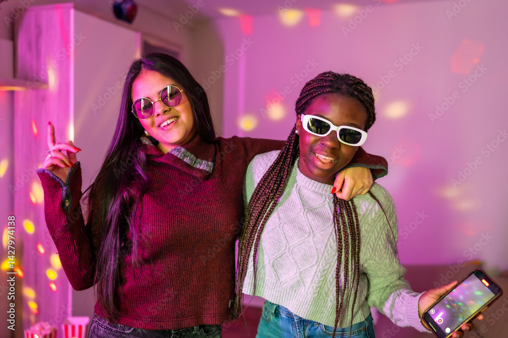 Two cheerful teenagers having fun at home party with disco lights