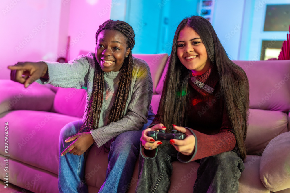 Two teenage girls playing video games at home, having fun and relaxing on sofa