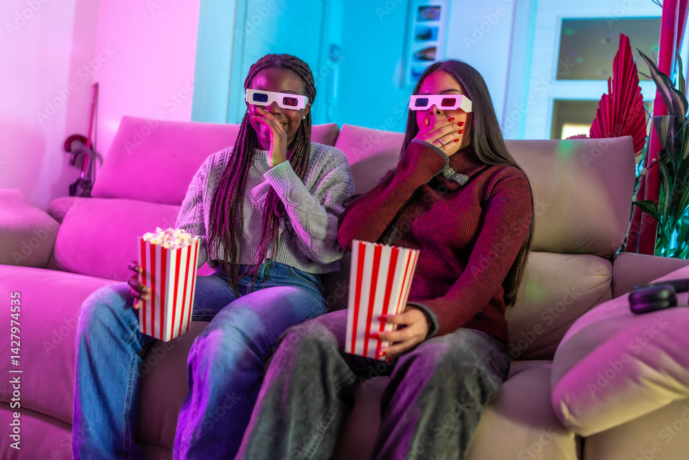 Two young women enjoying a 3d movie at home with popcorn