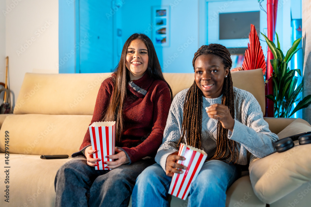 Smiling teen friends enjoying movie night with popcorn at home
