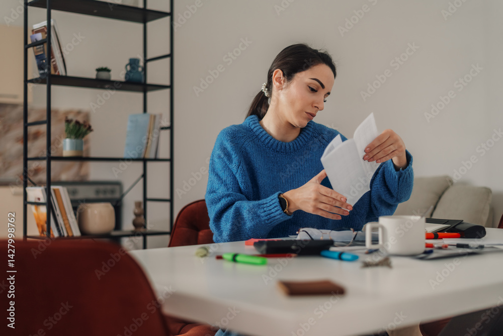 Woman managing home finances and reading documents at table Woman managing home finances and reading documents at table