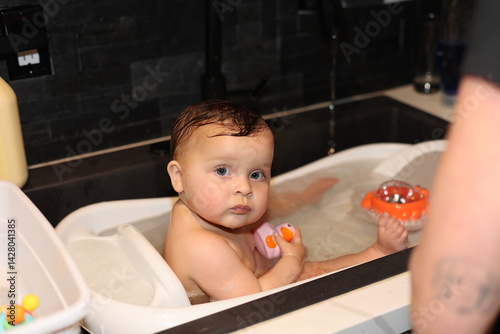 Cute Baby in bath with rubber ducky. 