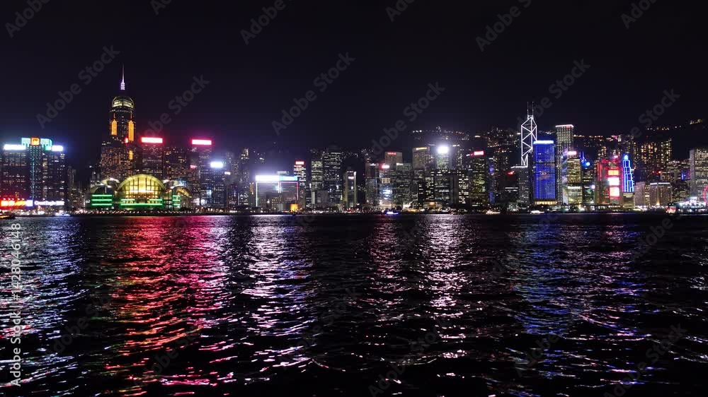 custom made wallpaper toronto digitalStunning nighttime skyline of Hong Kong featuring vibrant illuminated skyscrapers along the waterfront. Reflective water surfaces capture the colorful city lights, creating a captivating urban scene
