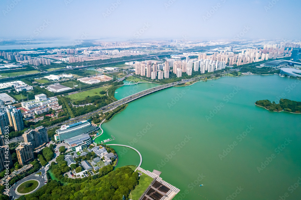 Obraz premium Skyline view of a vibrant urban landscape near a green lake showcasing modern architecture and extensive greenery