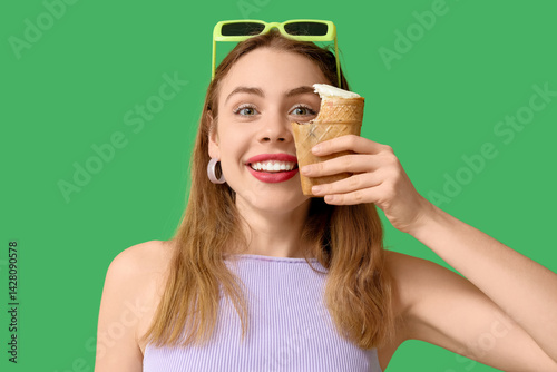 Happy smiling young woman with bitten vanilla ice cream in waffle cup on gree...