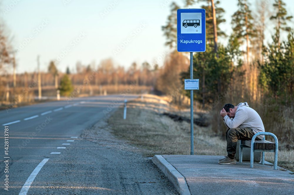 Man awaiting bus at stop during calm afternoon in rural setting