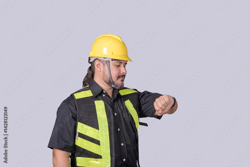 Studio shot of a barrel-chested construction worker in safety gear looking at his wristwatch, symbolizing time management on site. Studio shot of a barrel-chested construction worker in safety gear looking at his wristwatch, symbolizing time management on site.