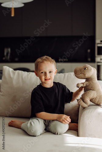 Smiling child playing with plush dinosaur toy on sofa in living room