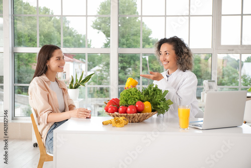 Mature female nutritionist working with client at table in office