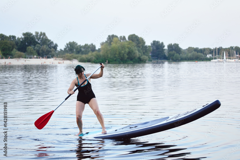 Woman Paddleboarding on Scenic Lake in Calm Outdoor Environment.. Woman Paddleboarding on Scenic Lake in Calm Outdoor Environment..