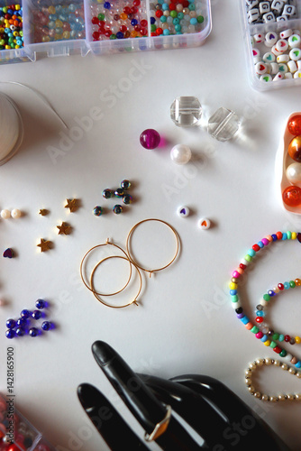 Obraz na płótnie Hand figurine, colorful friendship bracelets, necklaces, various beads and DIY supplies on the table. Making jewelry at home. Flat lay. w salonie