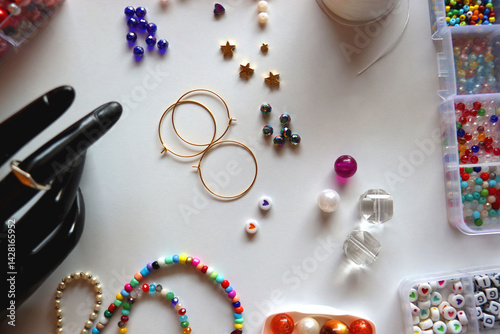 Obraz na płótnie Hand figurine, colorful friendship bracelets, necklaces, various beads and DIY supplies on the table. Making jewelry at home. Flat lay. w salonie