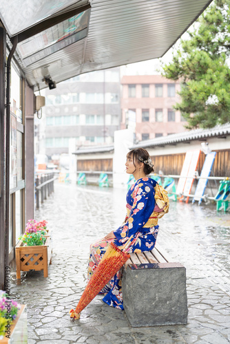 Obraz na płótnie It's a rainy summer day. bus stop. A Japanese woman in a teenager wearing a blue kimono folded and placed it by her side, sitting on a bench. w salonie