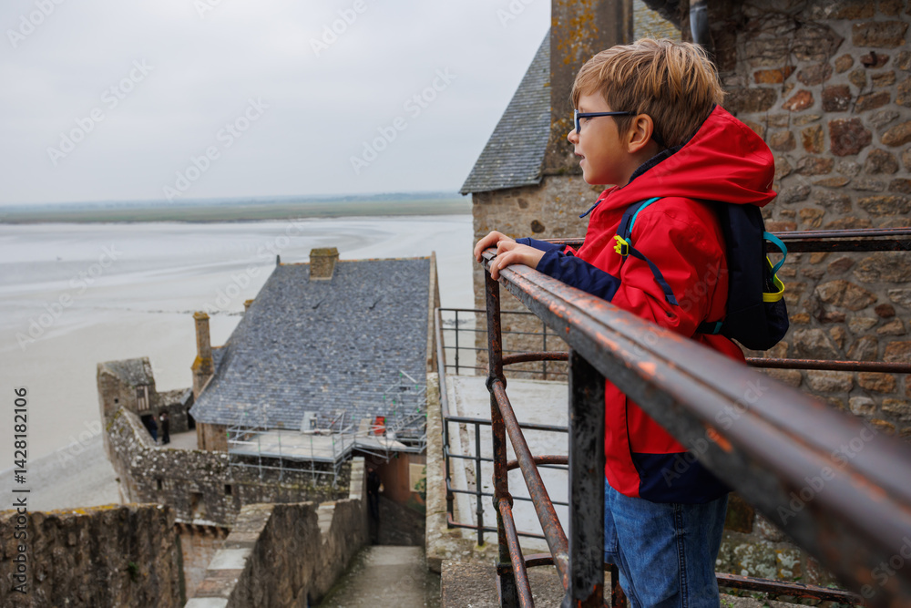 Kid gazes from Mont Saint Michel wall at the vast coastal view