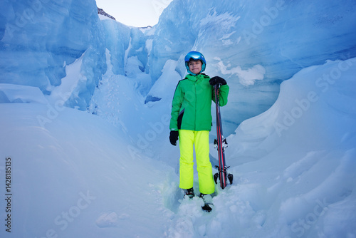 Obraz na płótnie Skier boy in bright gear stands amidst icy glacier formations w salonie