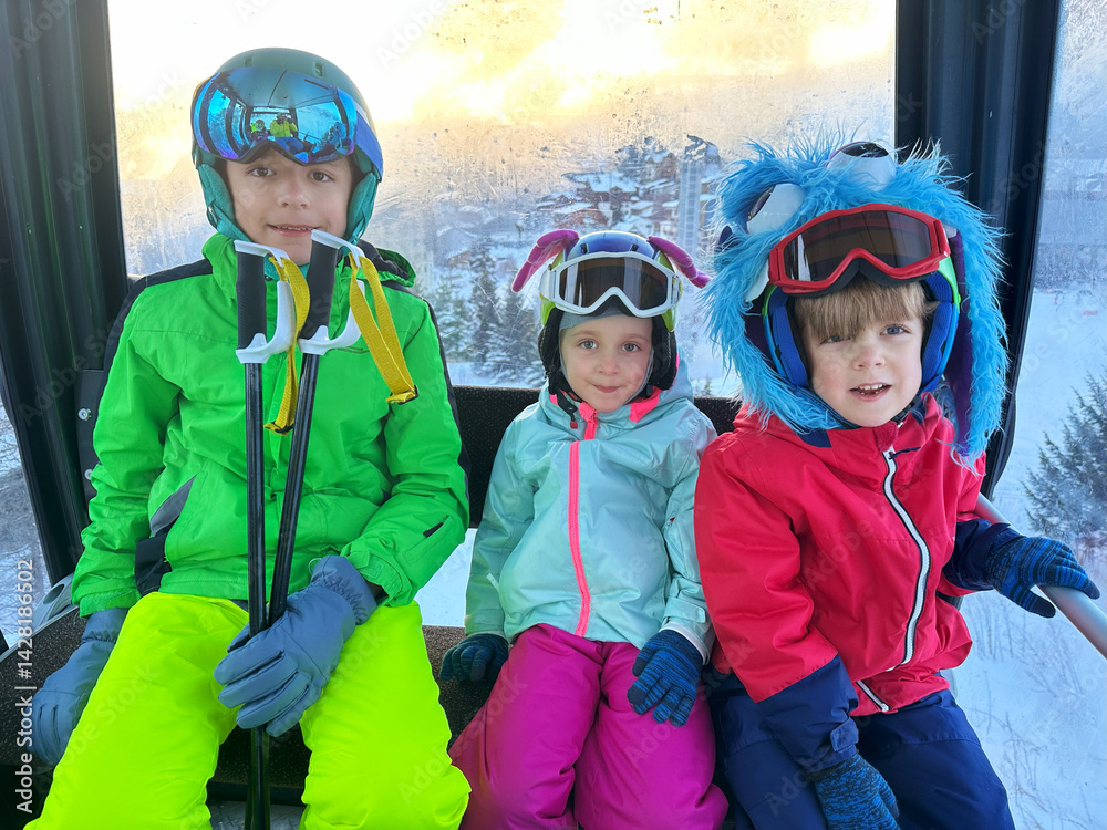 Three kids skiers enjoy a winter gondola ride in sunny morning