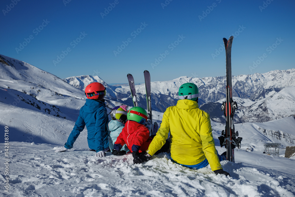 Vibrant-clad family sitting happily on a snowy mountain slope