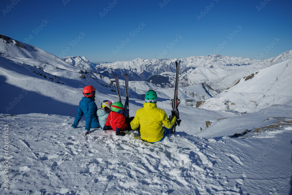 Family of four sit on the edge in breathtaking Alpine mountains