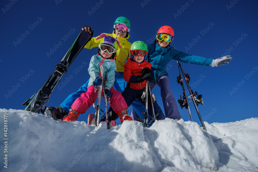Skier family in colorful gear pose on snowy slope under blue sky