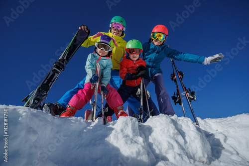 Obraz na płótnie Skier family in colorful gear pose on snowy slope under blue sky w salonie