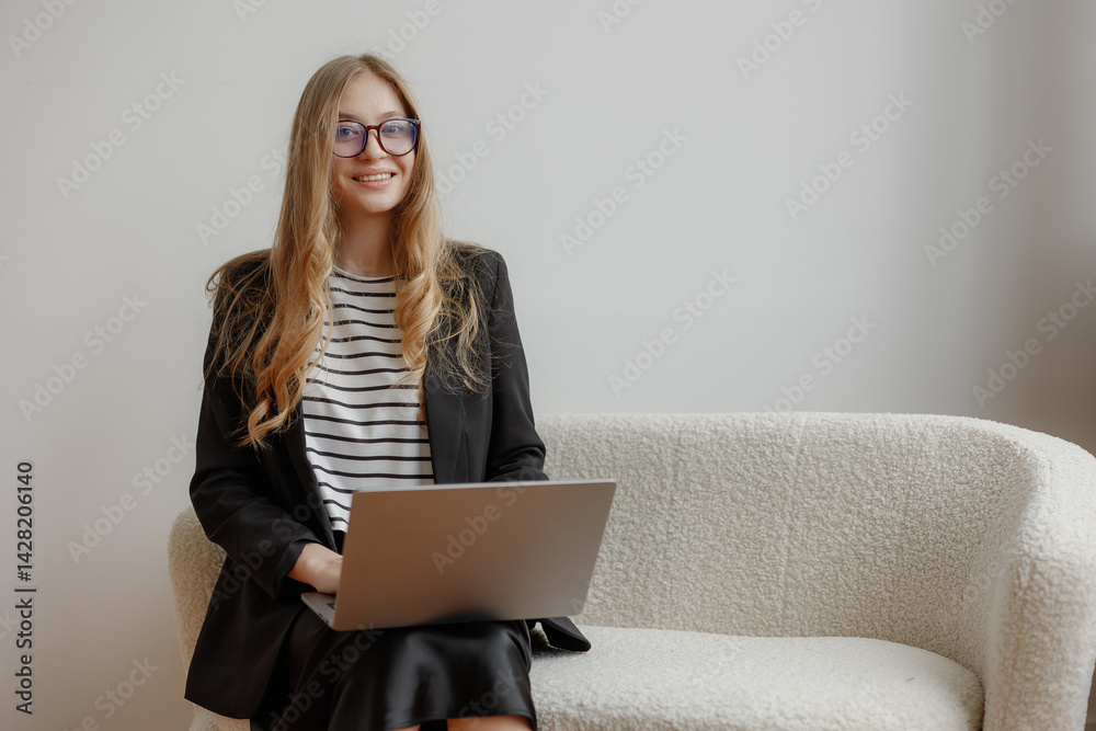 Young woman working on a laptop in a stylish office setting during the afternoon