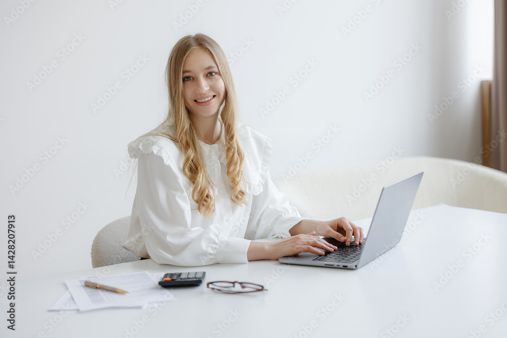 Professional woman working on laptop in bright office setting during daylight hours