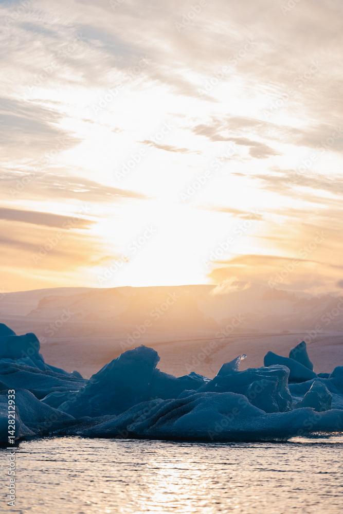 Shimmering ice formations on a glacial lake under the glowing sky of Iceland at dusk, blending warmth and chill in a surreal arctic scene.