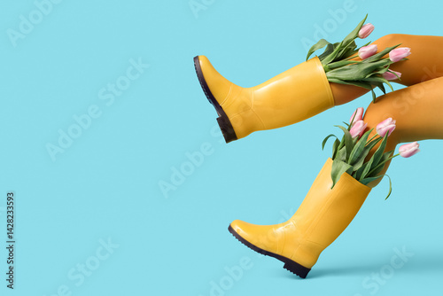 Schilderij op canvas Legs of woman in gumboots with tulips on blue background