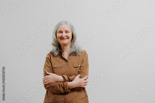 Obraz na płótnie Elderly woman smiling with crossed arms in a simple indoor setting during daylight hours w salonie