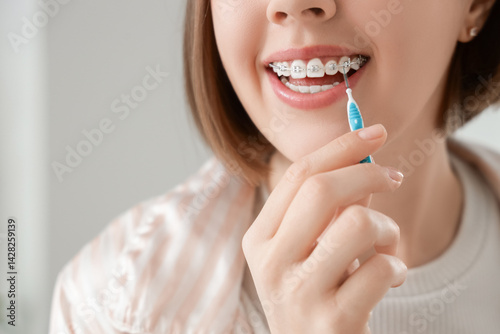 Obraz na płótnie Young woman with dental braces cleaning teeth in bathroom, closeup w salonie