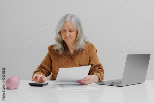 Obraz na płótnie Senior woman managing finances with calculator and documents during daylight w salonie